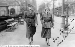 Two women wearing uniforms walk down the streets